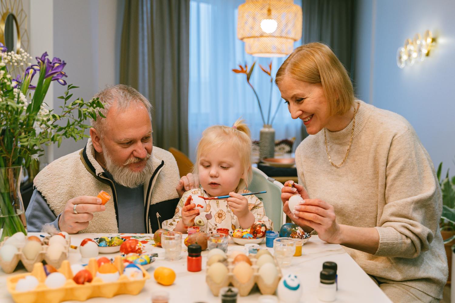 Grandparents painting eggs with granddaughter after learning difference between retirement planning vs financial planning.