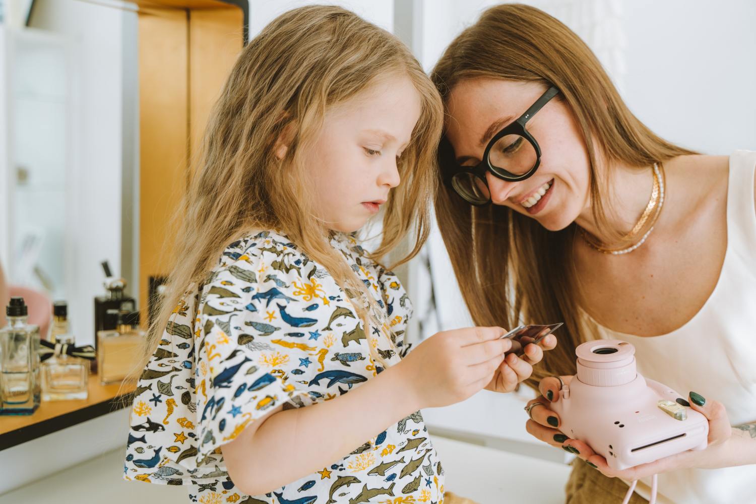 Mom and daughter looking at polaroid picture.